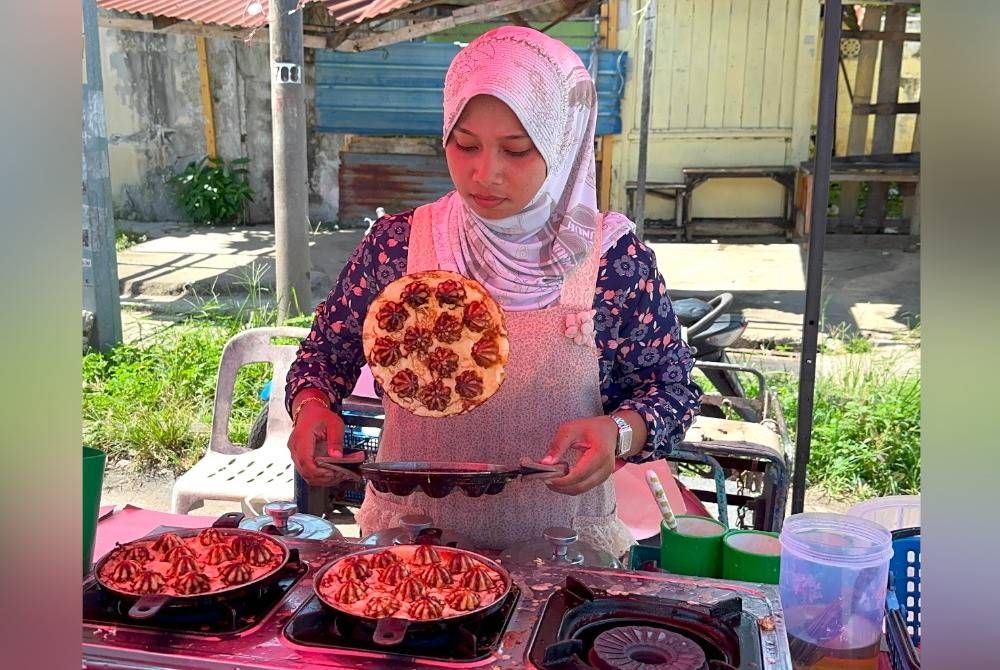 Mariyam melambung apam untuk menterbalikkan bahagian untuk dimasak.