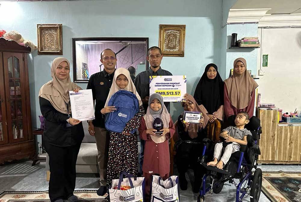 Ahmad Dasuki (belakang, kiri) bergambar bersama keluarga penerima manfaat Geran Sepadan Simpan SSPN Prime yang diadakan di Pasir Gudang, Johor.