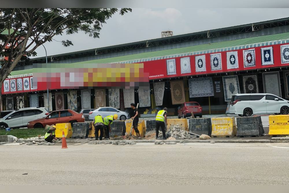 Kelihatan beberapa pekerja sedang membina semula bahu jalan.