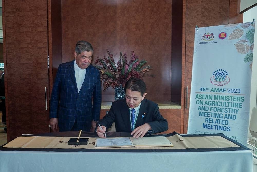 Miyashita menandatangani buku kunjungan hormat disaksikan Mohamad.