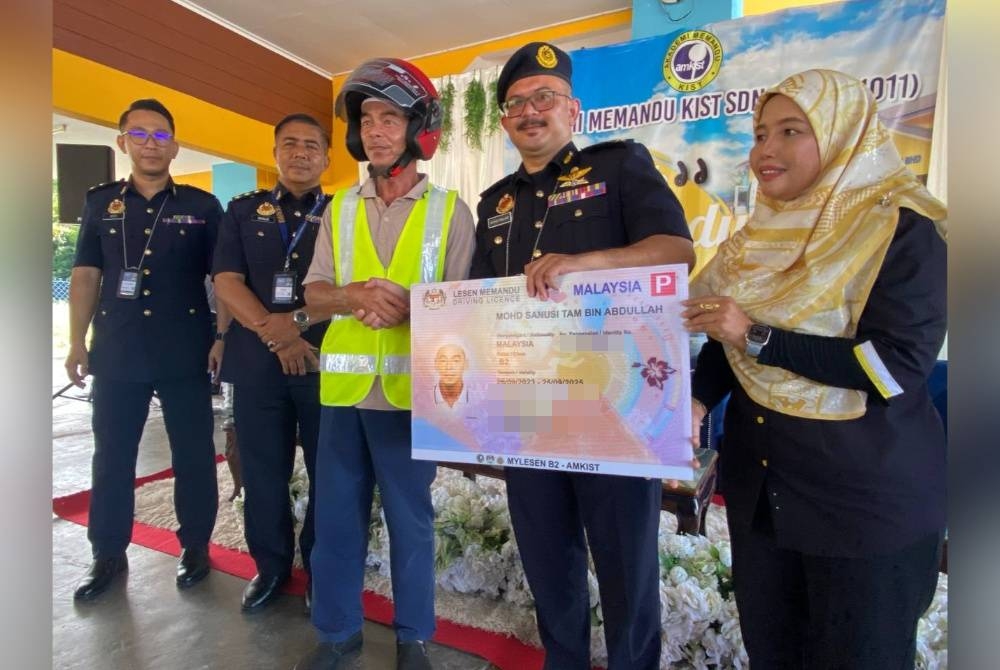 Mohd Misuari (dua dari kanan) menyampaikan lesen percuma kepada peserta, Mohd Sanusi Tam Abdullah berusia 59 tahun pada Majlis Penyerahan Lesen P Mylesen (B2) Percuma kepada 210 calon di Akademi Memandu KIST Telong, Bachok pada Khamis.