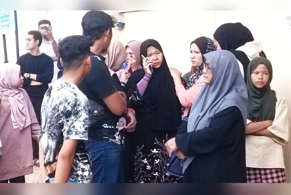 Radhiah (tengah) ketika membuat pengecaman mayat anaknya di Bilik Forensik Hospital Dungun pada Jumaat.