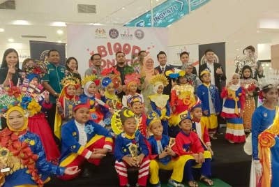 Masrudi (belakang, tengah) dan Enny Suhailis (belakang, lima dari kanan) serta Noorman (belakang, tiga dari kiri) bersama peserta pakaian beragam dalam Kempen Bazar Amal dan Kempen Derma Darah di pusat beli belah AEON Mall Kulaijaya, Kulai pada Jumaat.