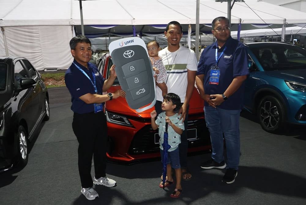 Mohd Nizam (kiri) menyampaikan replika kunci Toyota Vios kepada pemenang bertuah harian pada hari terakhir MSAM 2023 pada Ahad.
