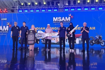 Mohamad (tiga dari kanan) dan Arshad (kanan) bergambar bersama tiga pemenang hadiah utama MSAM termasuk sebuah rumah teres bernilai RM500,000, sebuah kereta dan motosikal.