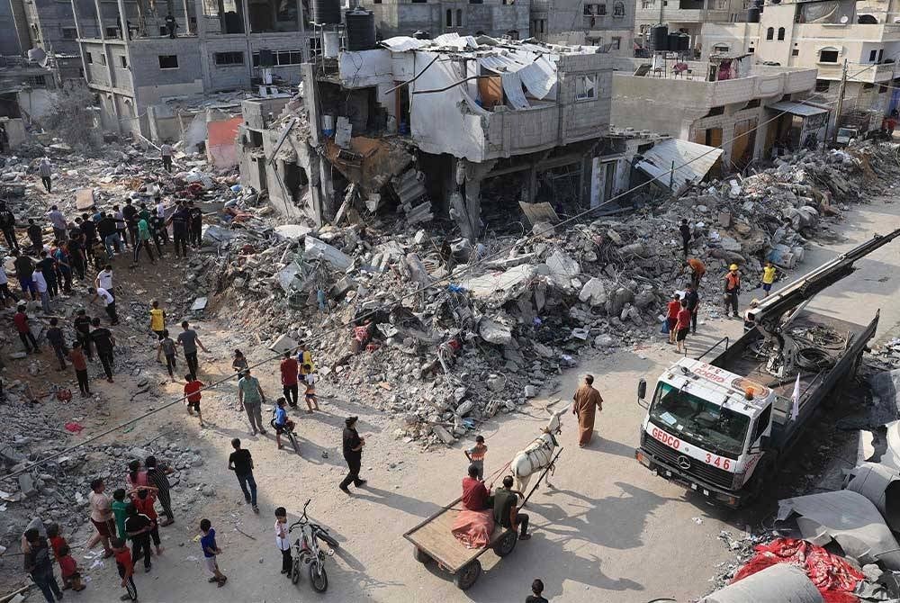 Rakyat Palestin melihat kemusnahan di sekitar runtuhan bangunan yang dilanda semasa serangan udara Israel ke atas Rafah di selatan Semenanjung Gaza. - Foto AFP