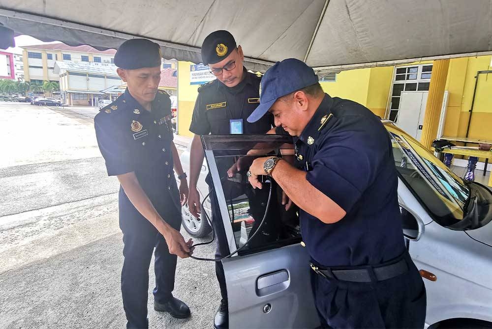 Zulkarnain (tengah) melihat anggotanya memeriksa ketelusan cermin gelap sebuah kenderaan di Ibu Pejabat JPJ Kuala Terengganu pada Selasa.