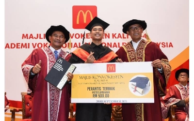 Pengarah Urusan dan Rakan Operasi Tempatan McDonald’s Malaysia, Datuk Azmir Jaafar (kanan) menyampaikan penghargaan kepada Muhammad Faris (tengah) yang berjaya menerima Anugerah Perantis Terbaik (Keseluruhan) sempena Majlis Konvokesyen Kali Ke-4 Akademi Vokasional McDonald's di UiTM Puncak Alam, di sini pada 25 September.
