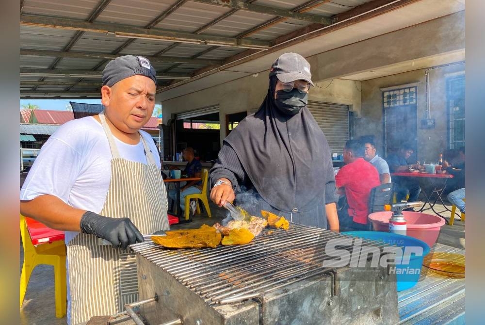 Md Rusmadi dibantu oleh pembantu membakar lidah dan daging lembu.