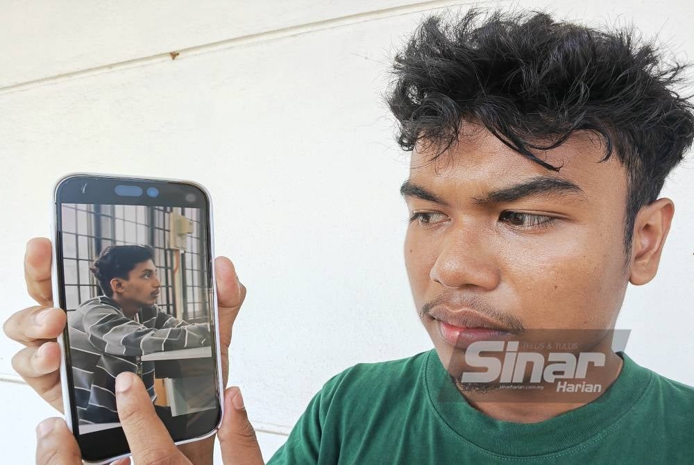 Muhammad Adib menunjukkan gambar Allahyarham Syed Ahmad Hafiy.