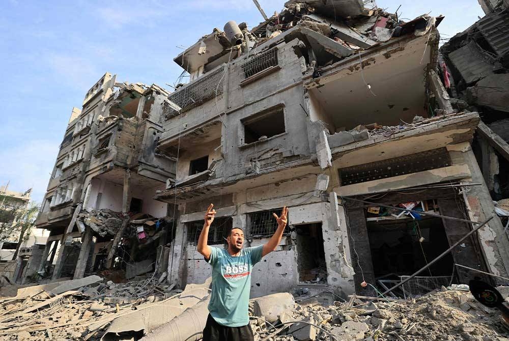 Seorang lelaki Palestin berdiri di tengah-tengah kemusnahan selepas pengeboman Israel di daerah al-Karama di Kota Gaza. - Foto AFP