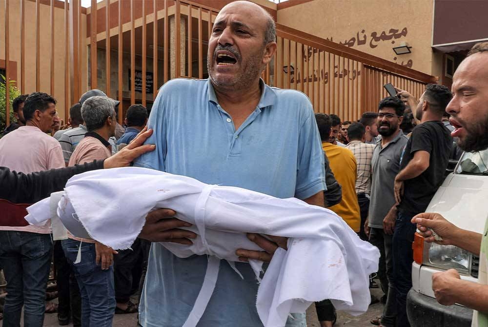 Seorang lelaki membawa jenazah anak kecil yang terbunuh dalam serangan udara rejim Zionis di Khan Yunis. - Foto AFP