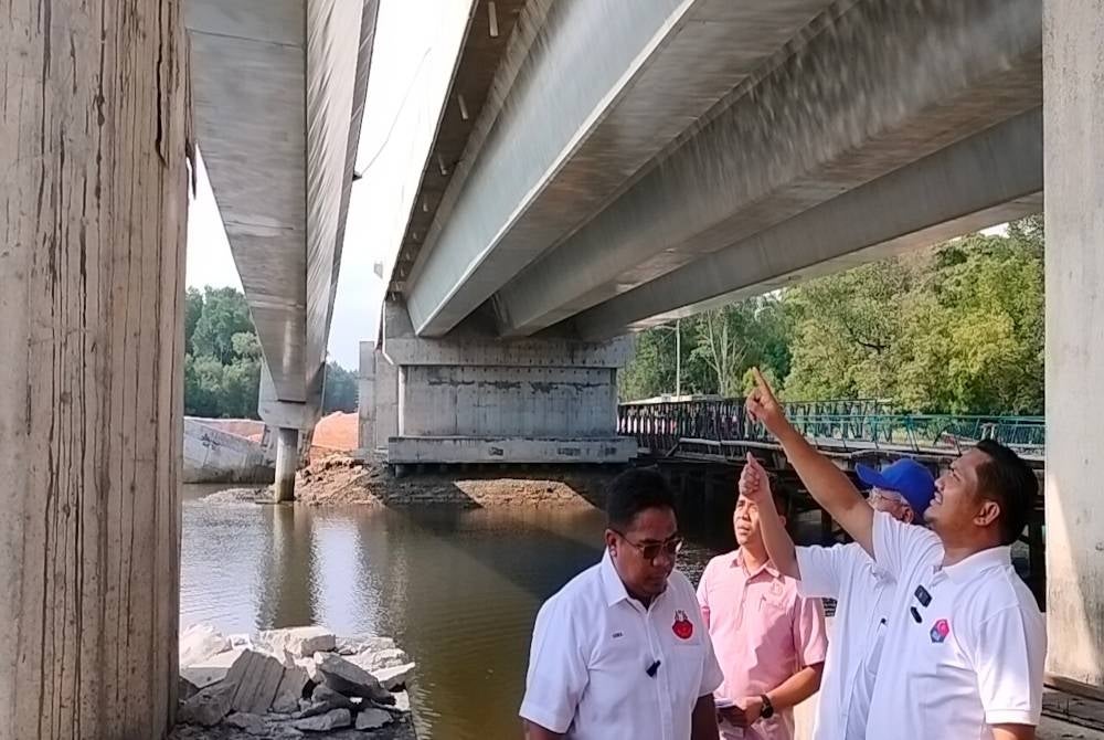 Mohamad Fazli (kanan) menunjukkan struktur binaan jambatan utiliti yang runtuh di Kampung Perigi Acheh, Pasir Gudang.