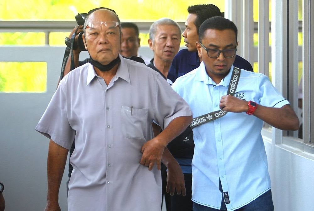 Chong Sing Chai (kiri) diiring pegawai LHD ketika hadir di mahkamah pada Jumaat.