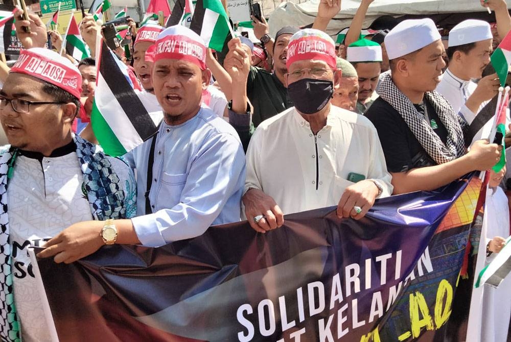 Orang ramai memegang kain rentang ketika melancarkan Tabung Solidariti Rakyat Pelestin.