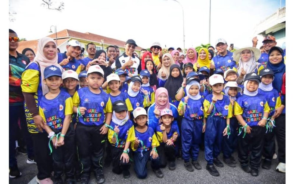 Fadhlina (duduk, tengah) bersama-sama murid sekolah yang menyertai Program Kecergasan KPM yang diadakan sempena sambutan HSN 2023 di Kangar, Perlis.

