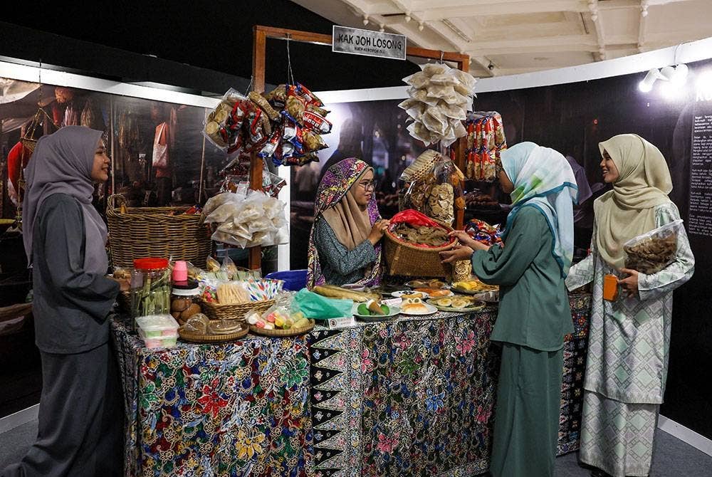 Pelajar Sekolah Menengah Kebangsaan Haji Abdul Rahman Limbong, Nur Fitri Salwa Apiyang@Mohamad, 18, (tiga, kanan) bersama rakan-rakan merasai pengalaman 'berniaga' seperti zaman dahulu semasa melawat Pameran Dapo Mok Kite: Gastronomi Alam Melayu 2023 di Kompleks Muzium Negeri Terengganu hari ini.