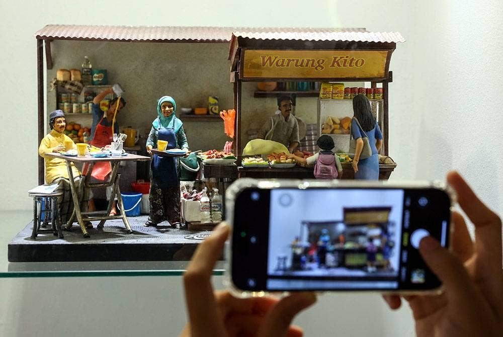 Pelajar Sekolah Menengah Kebangsaan Haji Abdul Rahman Limbong, Nurul Huda Nabihah Rosli merakamkan gambar 'miniatur' warung pada zaman dahulu semasa melawat Pameran Dapo Mok Kite: Gastronomi Alam Melayu 2023 di Kompleks Muzium Negeri Terengganu hari ini.