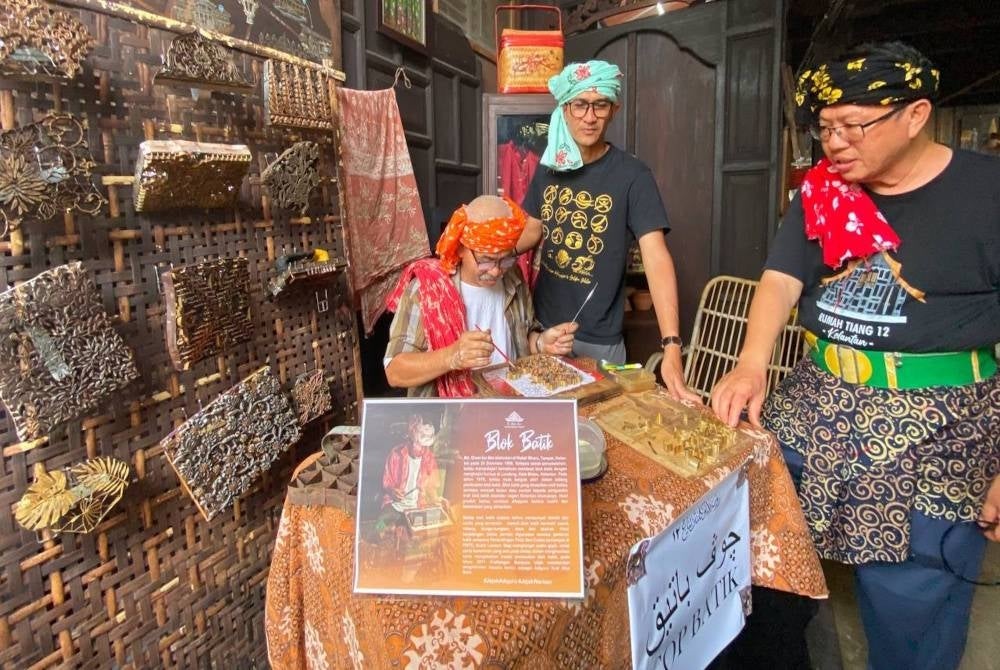 Wan Eikmal (tengah) melihat bakat seorang adiguru yang mahir membuat blok batik semasa Jejak Warisan Adiguru Tourism Wilayah Timur di Rumah Melayu Kelantan Tiang 12 di Kota Bharu.