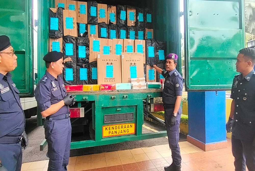 Sazali (dua dari kanan) menunjukkan kotak berbalut plastik hitam yang mengandungi rokok putih tidak bercukai.