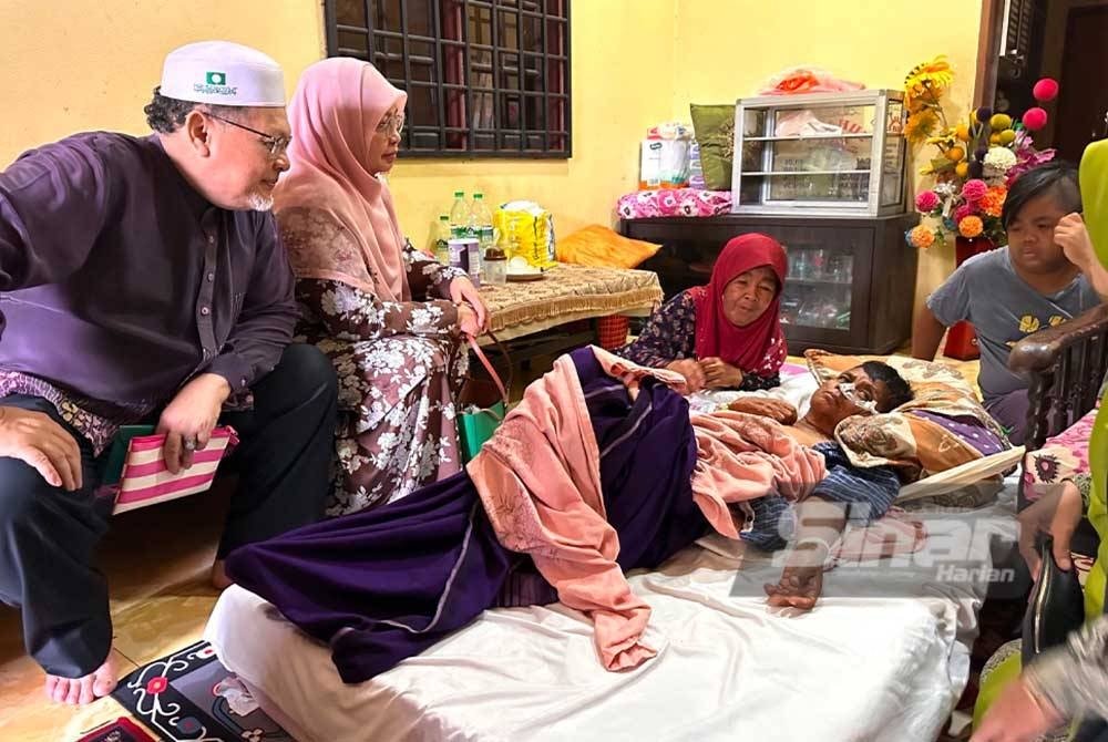 Mohd Amar (kiri) yang menziarahi pesakit terlantar di Kampung Telok, Panji, Kota Bharu pada Selasa.