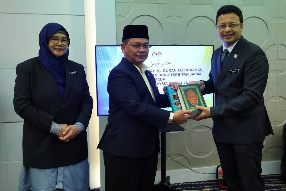 Mohd Na'im (tengah) menyerahkan Naskah Al-Quran kepada Duta Besar Malaysia ke Ireland, Wan Aznainizam Yusri Wan Abdul Rashid (kanan) pada Majlis Penyerahan Sumbangan Naskhah Al-Quran Terjemahan Bahasa Inggeris dan Buku Terbitan JAKIM di Kompleks Islam Putrajaya (JAKIM), pada Selasa. - Foto Bernama