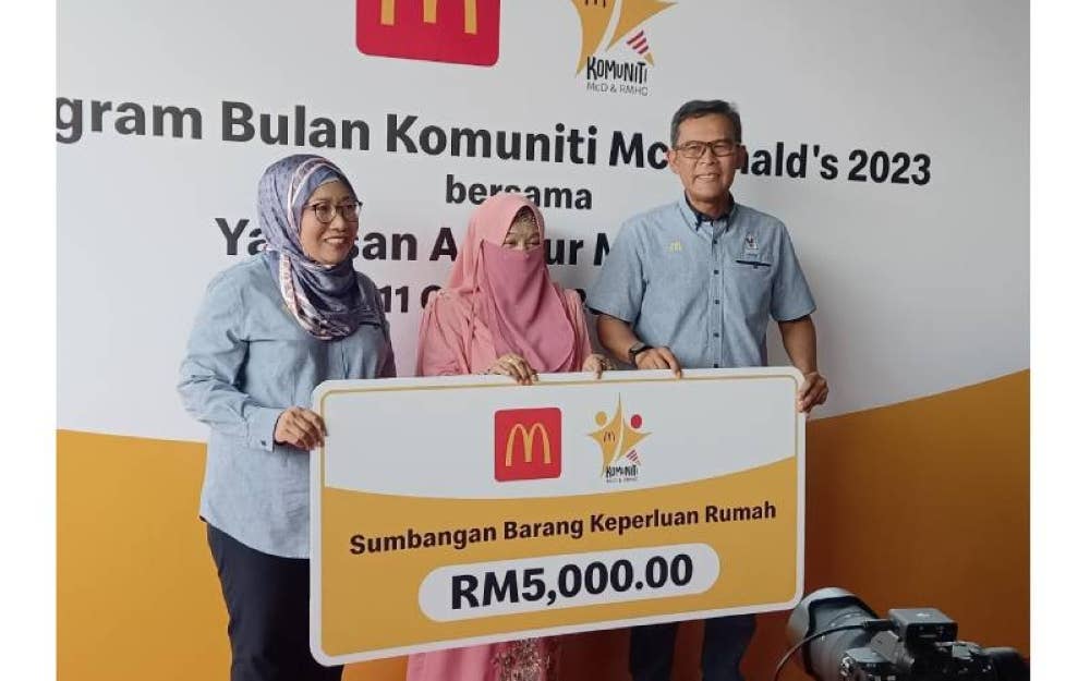 Azmir (kanan) menyerahkan sumbangan barang keperluan rumah berjumlah RM5,000 kepada Dr Fazillah (tengah) sambil ditemani Pengarah Komunikasi Korporat McDonald's Malaysia, Shamsidar Yahya.
