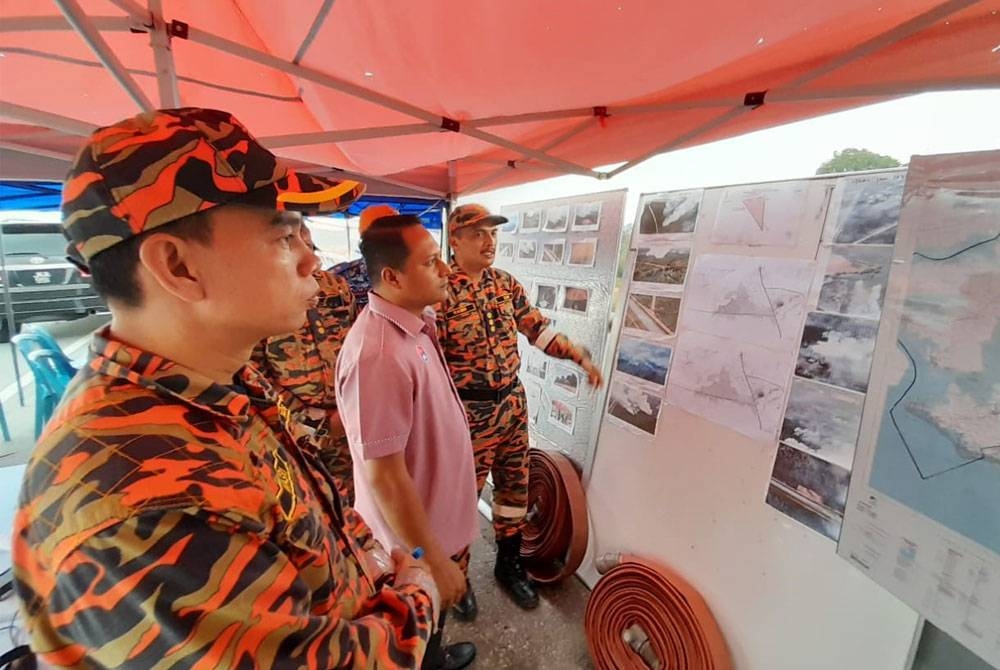Aznan (kiri) ketika mendengar taklimat daripada Rasidi (kanan) di pangkalan operasi di Bypass Sebana Cove-Punggai, Kota Tinggi, pada Rabu.