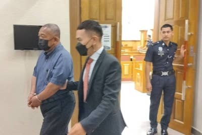 Tertuduh diiringi pegawai SPRM keluar dari mahkamah selepas dituduh atas 12 pertuduhan menerima suapan berkait kerja-kerja pengurusan jenazah di HoSHAS antara tahun 2021 hingga 2022.