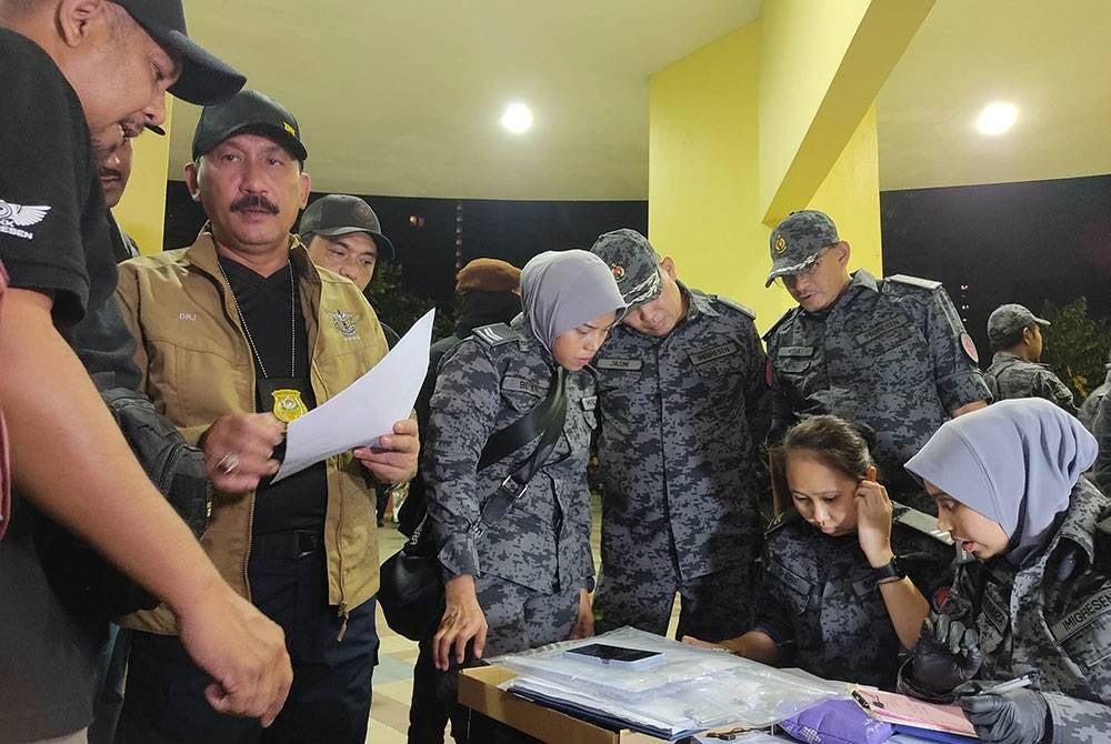 Ruslin (dua kiri) meninjau proses dokumentasi yang dilaksanakan pegawainya dalam serbuan di sebuah kondominium di Kuala Lumpur, pada Jumaat.