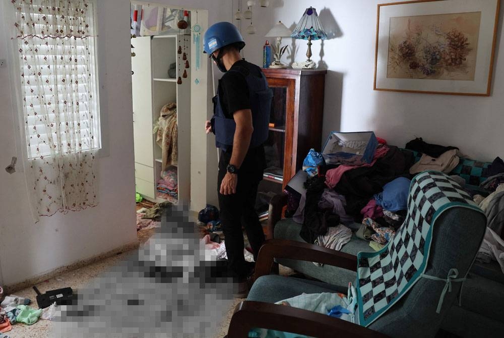 Seorang wartawan asing memeriksa kesan darah di lantai sebuah rumah di kibbutz Nir Oz di sepanjang sempadan dengan Semenanjung Gaza. Foto AFP