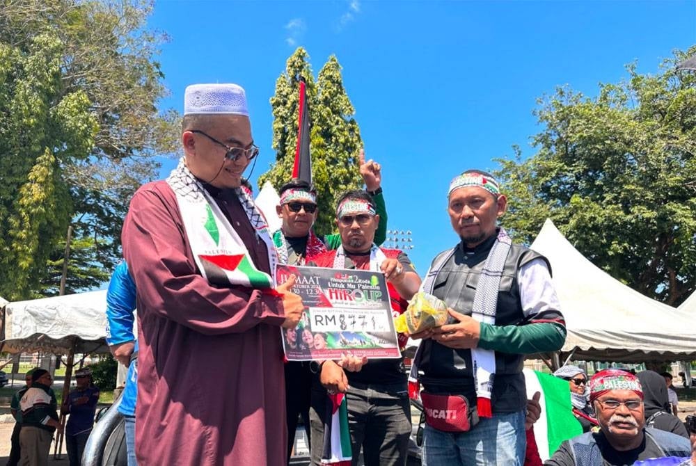 Suhaizly (kanan) menyerahkan wang kutipan kepada Nik Hamid (kiri) untuk disumbangkan pada Palestin.