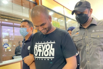 Tertuduh (tengah) tersenyum ketika wajahnya dirakam media di Kompleks Mahkamah Butterworth pada Jumaat.