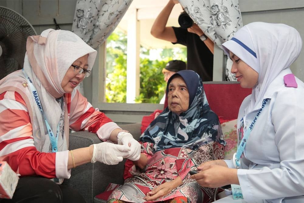 Menteri Kesihatan, Dr Zaliha Mustafa (kiri) melakukan perkhidmatan saringan kesihatan kepada warga emas, salah seorang daripada kumpulan sasar Mobile Truck WoW. - Foto sumber KKM
