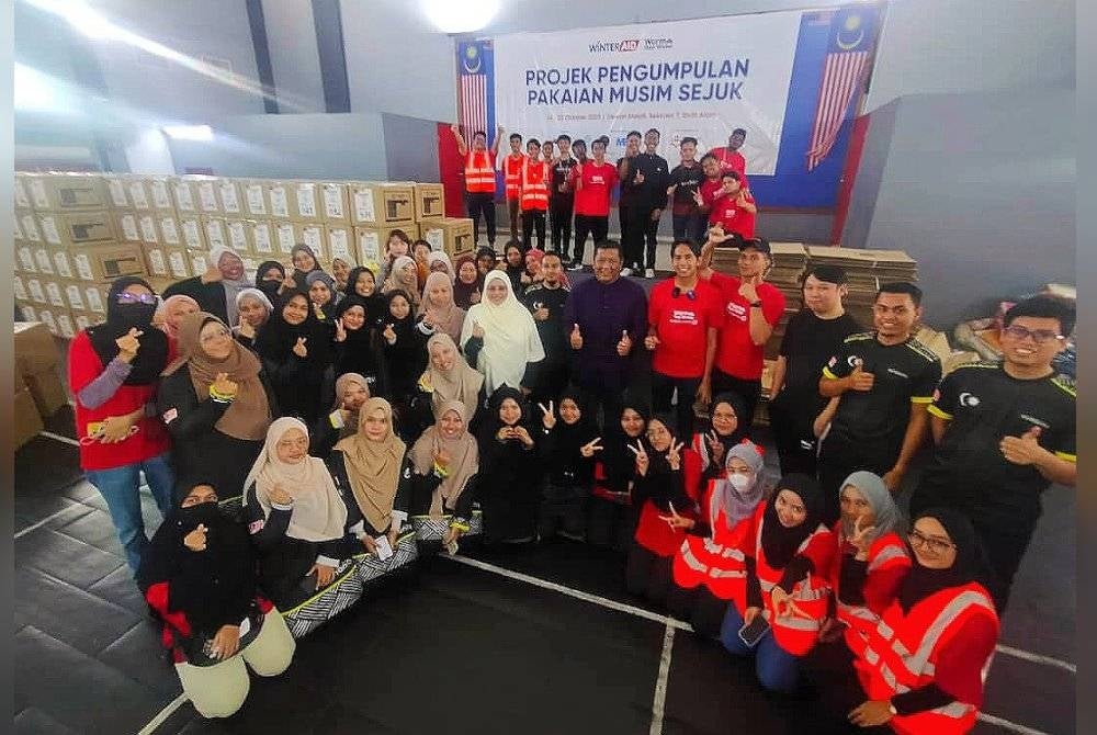 Siti Sakinah (barisan kedua: enam dari kiri) dan Nik Justin (barisan kedua, berdiri enam dari kanan) bersama sukarelawan dan ahli Syria Care pada majlis penutup Projek Pengumpulan Pakaian Musim Sejuk di Dewan Melati Seksyen 7, di Shah Alam pada Ahad.