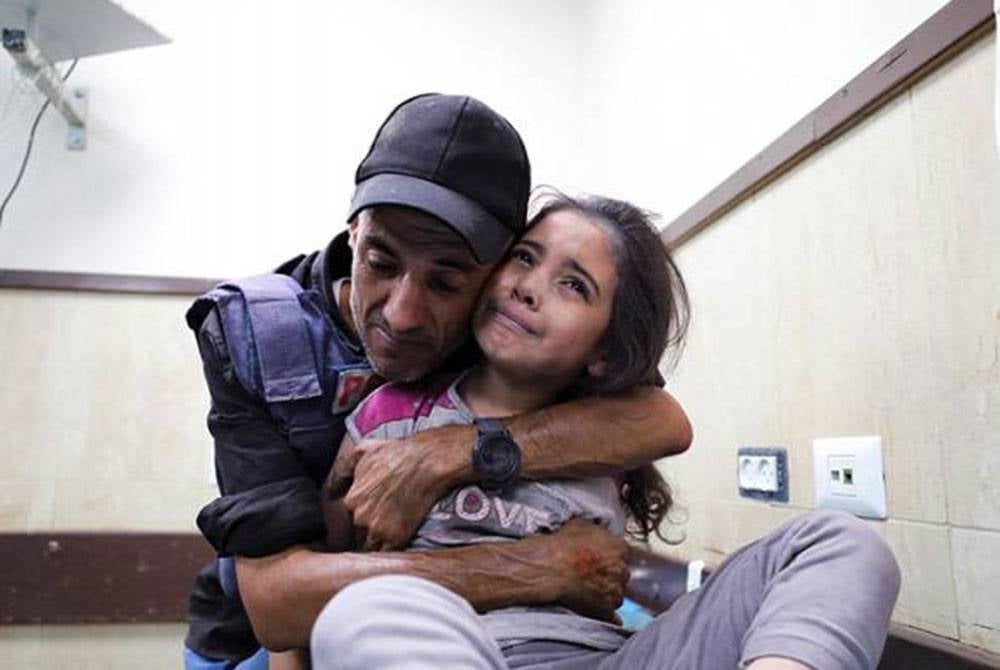 Seorang wartawan warga Palestin memeluk anak buahnya yang cedera susulan serangan tentera rejim Zionis Israel ke atas rumahnya di kem pelarian Nusseirat, Semenanjung Gaza. - Foto: AP