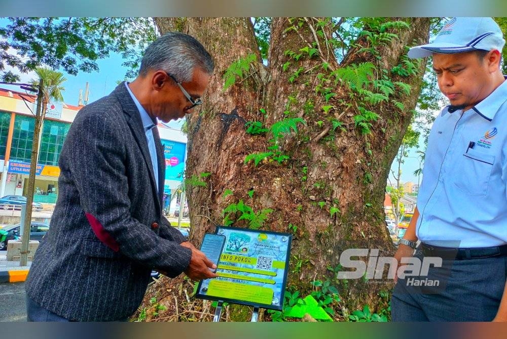 Suris(Kiri) dan Mohd Yusri menunjukkan pengimbas yang boleh diakses orang ramai untuk mengetahui spesies, umur, nilai pokok yang telah ditanda