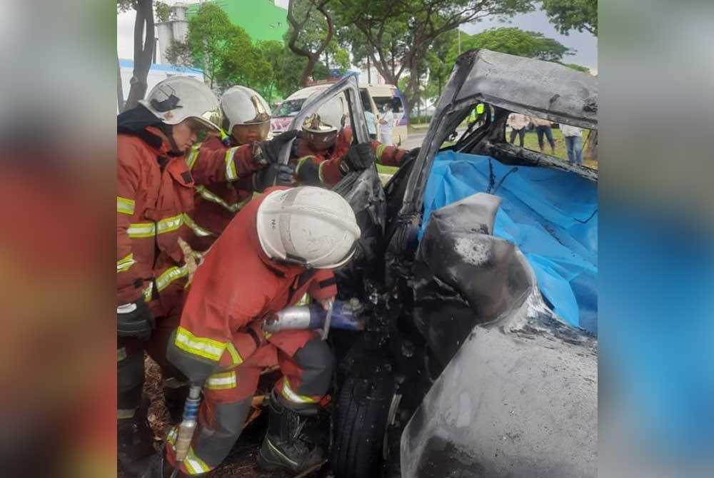Anggota bomba mengeluarkan mayat seorang pemandu yang rentung selepas kereta dipandunya terbabas dan melanggar sebatang pokok di Kawasan Perindustrian Pasir Gudang, Pasir Gudang pada Isnin.