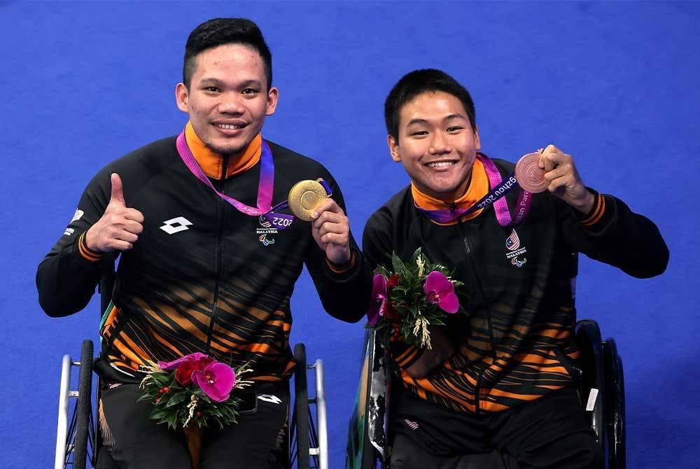 Muhammad Nur Syaiful (kiri) mendapat pingat emas pertama negara meraikan kejayaan bersama rakan sepasukan, Lee Ker pada temasya Sukan Para Asia Hangzhou 2022 di Arena Akuatik Hangzhou malam ini. - Foto Bernama
