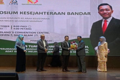 Borhan (tengah) menerima cenderahati daripada Juhari dalam satu majlis di Pusat Konvensyen Midland di Seksyen 7 di Shah Alam pada Isnin.