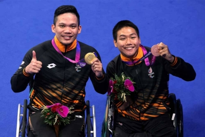 Muhammad Nur Syaiful (kiri) mendapat pingat emas pertama negara meraikan kejayaan bersama rakan sepasukan, Lee Ker pada temasya Sukan Para Asia Hangzhou 2022 di Arena Akuatik Hangzhou malam ini. - Foto Bernama