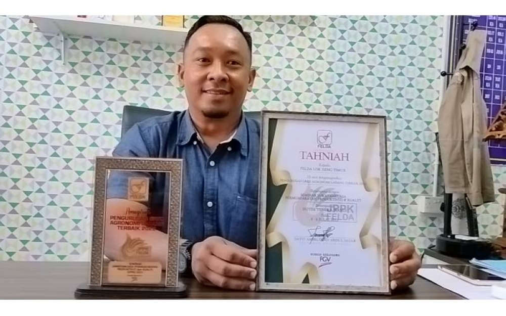 Mohd Norazlan menunjukkan anugerah Pengurusan Gred Agronomi Ladang Terbaik yang dimenangi Felda Lok Heng Timur selama enam tahun berturut-turut.