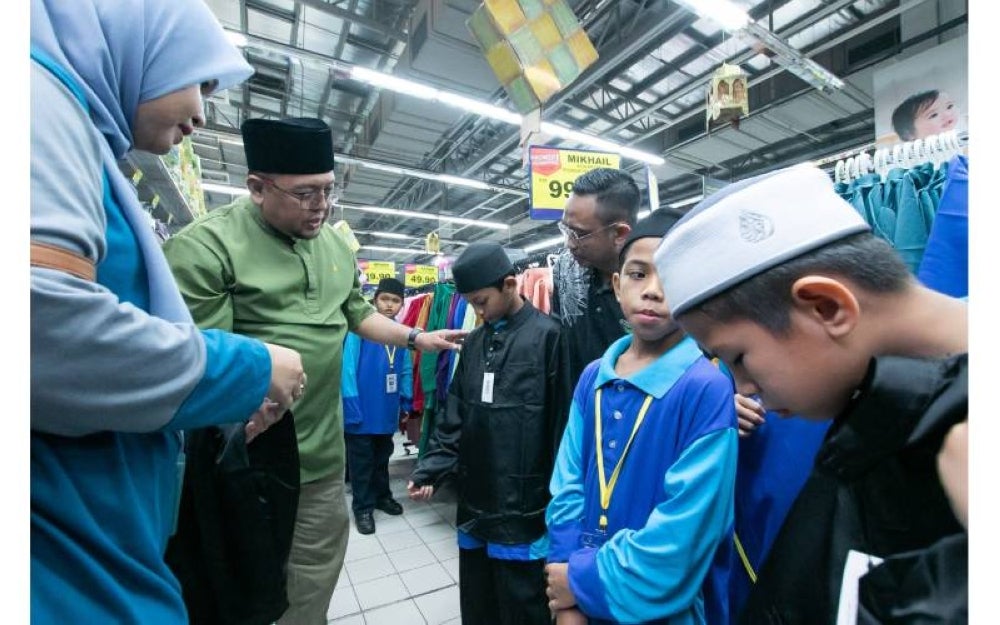 Amran (dua dari kiri) menyantuni penghuni Inapan Kasih Sayang (IKS) memilih pakaian sempena Hari Raya Aidilfitri lalu. 