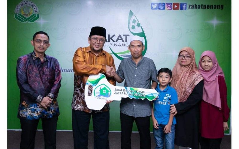 Amran (dua dari kiri) menyerahkan replika kunci rumah kepada seorang penerima Skim Inapan Kasih di bawah ZPP. 