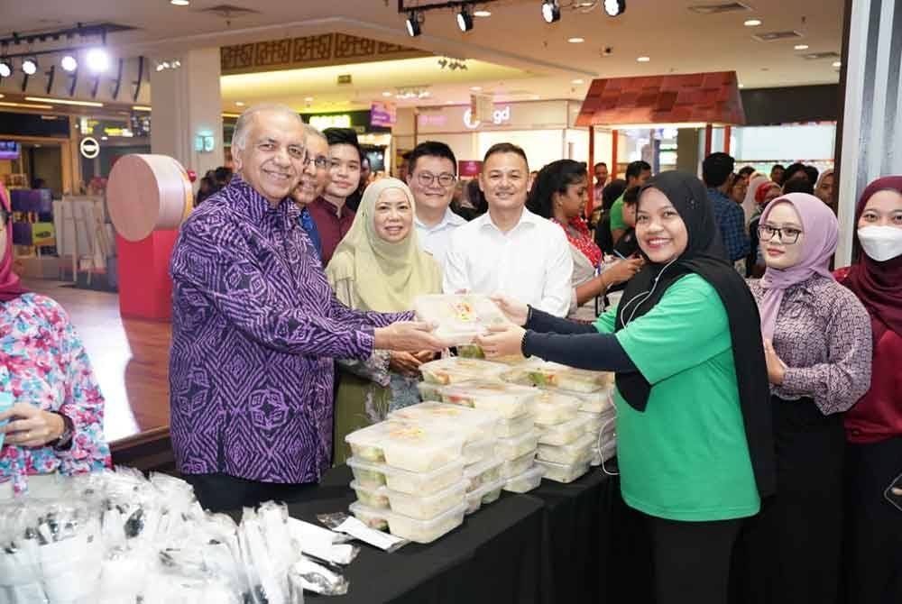 Ameer (kiri) mengedar hidangan pasta sempena sambutan Hari Pasta Sedunia di Mydin USJ pada Rabu.