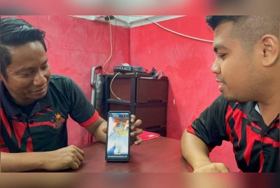 Muhammad Alif (kanan) bersama rakan, Muhammad Afnan Mohd Nor melihat video kenangan bersama Allahyarham Mohamad Elias. - Foto Ehsan The Star