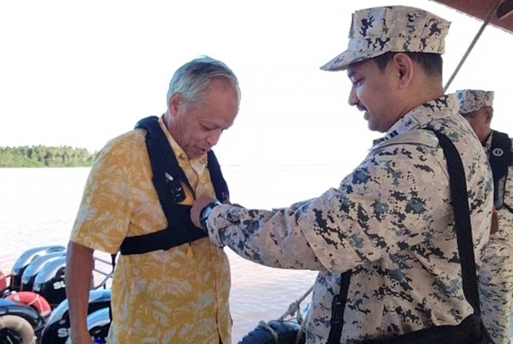Muhammad Nasir (kiri) memakai jaket keselamatan sebelum menyaksikan proses penenggelaman bot nelayan asing bersama tukun tiruan di muara Kuala Besar pada Jumaat.