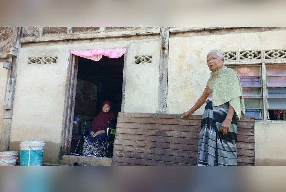 Che Noor dan Badariah menunjukkan rumah mereka yang terjejas banjir.