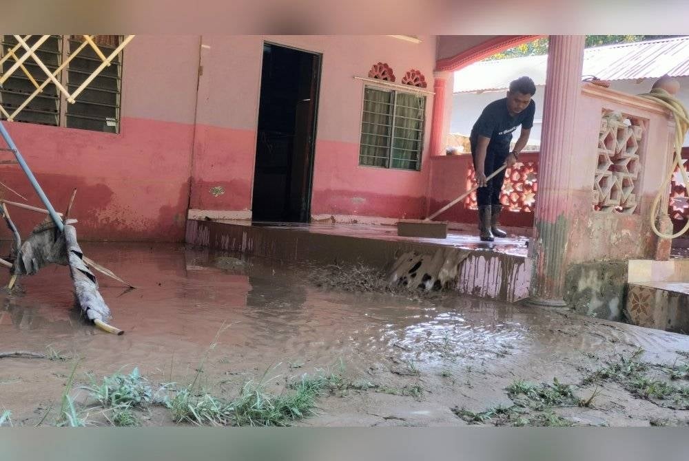 Mohammad Hazarul Azan sedang mencuci rumah keluarga di Kampung Baru yang dinaiki air pada Khamis.