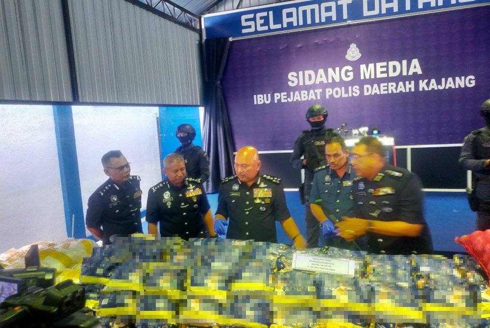 Mohd Kamarudin (tengah) melihat dua jenis dadah yang dirampas ketika diseludup masuk ke dalam negara dari Pakistan menerusi tiga serbuan pada Rabu.
